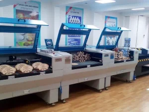 Açık kapaklı üç adet ahşap lazer kesim makinesi üzerinde kesilmiş ahşap ürünler görülüyor.