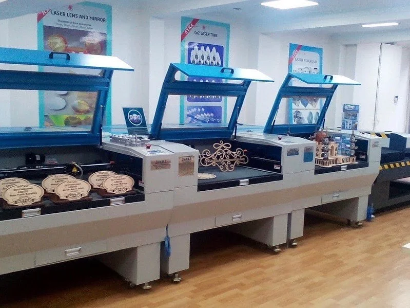 Açık kapaklı üç adet ahşap lazer kesim makinesi üzerinde kesilmiş ahşap ürünler görülüyor.